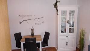 Un coin repas avec une table et des chaises, un meuble avec des portes en verre et une carte géographique murale.
