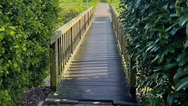 Un puente de madera que conduce a una colina con un cartel.
