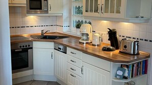 Una cocina con armarios blancos, microondas, tostadora y cafetera.