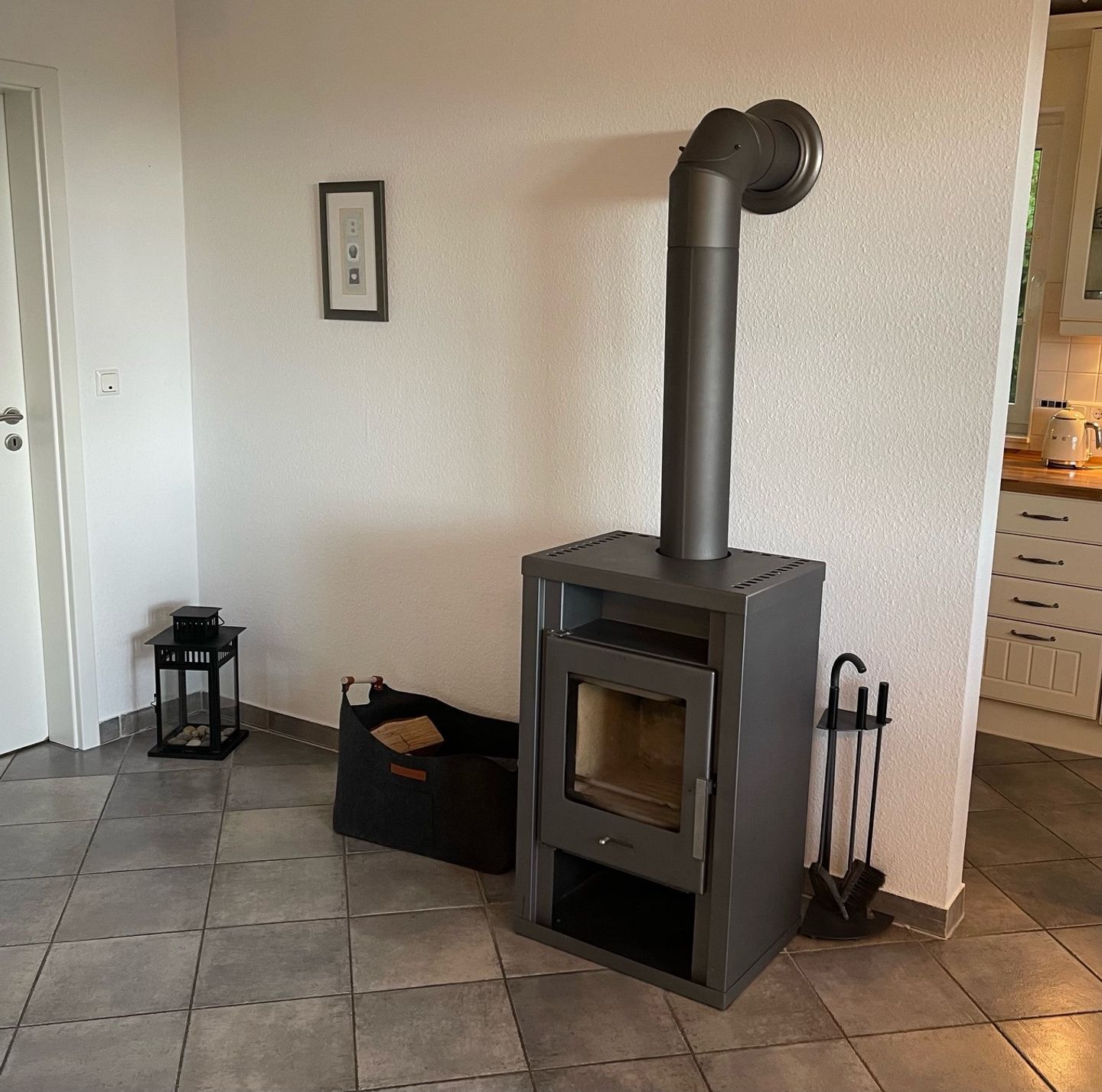 Eine moderne Küche mit eingebautem Holzofen, einem kleinen schwarzen Tisch und einem Bild an der Wand.