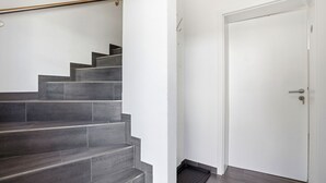 Eine Treppe mit dunklen Fliesen, einer weißen Tür mit Schlüsselloch und einem Metallgeländer.