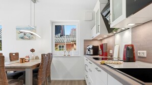 Eine kompakte Küche mit Essbereich, Blick auf ein Haus durch ein Fenster und modernen Geräten.