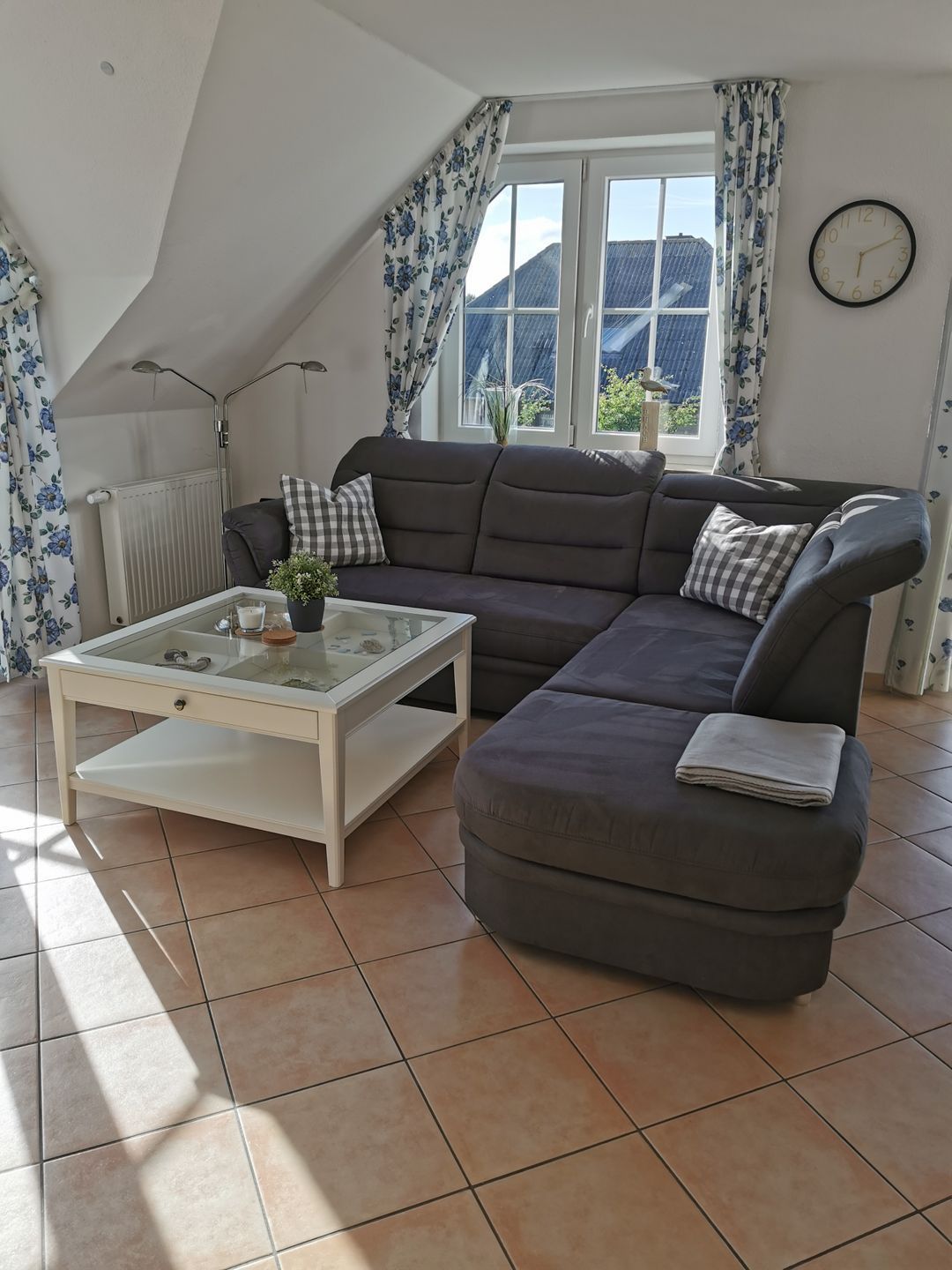 Una sala moderna con un sofá seccional, una mesa de centro de vidrio y vistas al exterior a través de un ventanal.