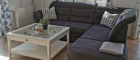 Una sala moderna con un sofá seccional, una mesa de centro de vidrio y vistas al exterior a través de un ventanal.