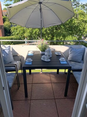Patio con tavolo apparecchiato per il tè, sedute all'aperto e un ombrellone grande.