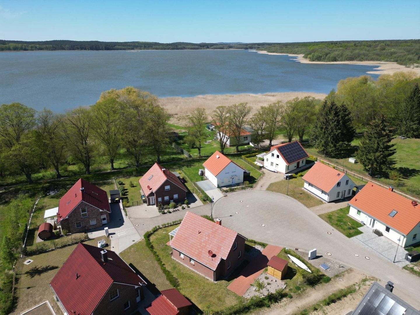 Zona residencial com casas, um grande corpo d'água e uma praia arenosa.