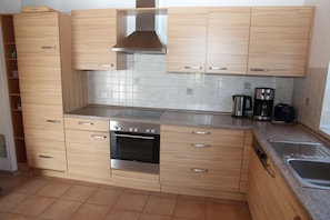 A modern kitchen with wooden cabinets, a built-in oven, a coffee maker, and a toaster.