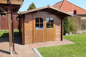 A wooden cabin with a sloped roof, a large window, and a door.