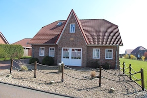 A brick house with a red-tiled roof, a white garage door, and a small window with a skylight.