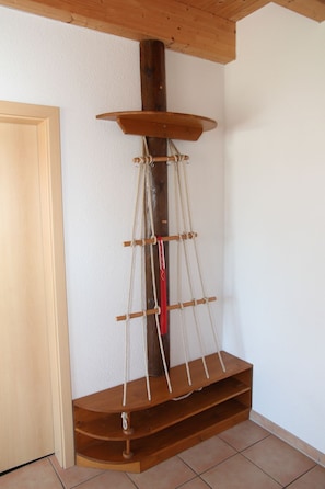 A corner room with a wooden shelf unit against the wall, a door, and tiled flooring.