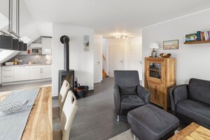 Una sala de estar moderna con un sofá, un reposapiés y un mueble de madera.