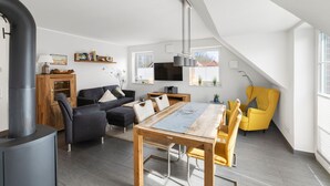 Un loft moderno con comedor, un conjunto de sofás, un sillón amarillo y una estufa negra grande.