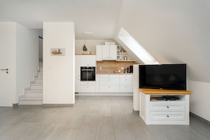 Una cocina moderna con armarios blancos, encimera de madera y horno empotrado.