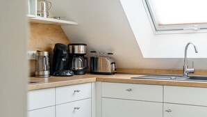 Una cocina con encimera de madera, armarios blancos, cafetera, tostadora y un lavabo con grifo moderno.