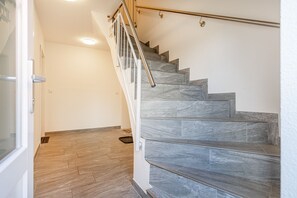 Una escalera de piedra gris con barandilla de metal, que conduce a una puerta.