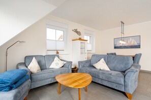 A living room with two grey sofas, a wooden coffee table, and a painting of a sailboat on the wall.