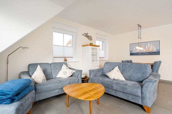 Ein Wohnzimmer mit zwei grauen Sofas, einem Holztisch und einem Bild eines Segelboots an der Wand.