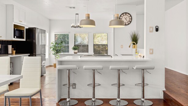 A modern kitchen with white cabinetry, stainless steel appliances, and a central island with bar stools. - Modern 5 Bedrooms in SA Chef Kitchen, Game Lounge (San Antonio)