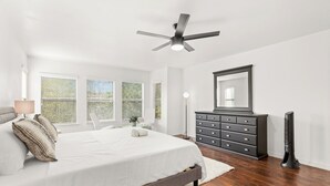 A bedroom with a bed, a dresser, a ceiling fan, and a large window with blinds. - Modern 5 Bedrooms in SA Chef Kitchen, Game Lounge (San Antonio)