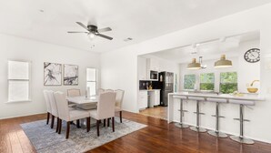 A modern kitchen with white cabinets, a black refrigerator, and a bar area with stools. - Modern 5 Bedrooms in SA Chef Kitchen, Game Lounge (San Antonio)