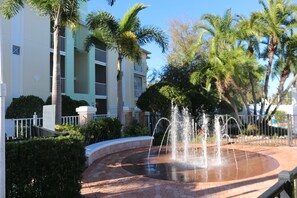 Stunning outdoor oasis with a serene water feature, surrounded by lush greenery and a low fence.