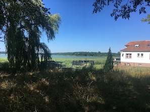 Ein Haus mit rotem Dach, einer Satellitenschüssel und Blick auf einen See und Wald im Hintergrund.