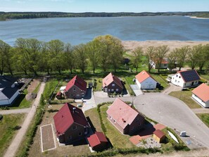 A residential area with houses, a paved road, and a lake in the background. - Alleenhuus - Hochwertiges und Luxuriöses Ferienhaus Direkt am Wariner See (Warin)
