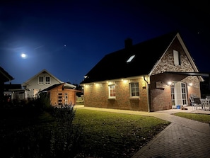Una casa de ladrillo con un porche bien iluminado y un letrero que dice