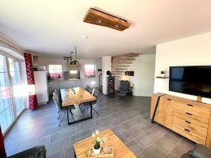 A modern living space with a dining area, kitchen, and a TV.