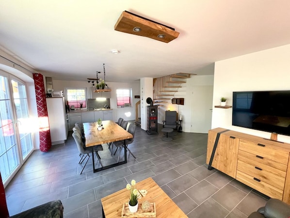 Un espacio habitable moderno con comedor, cocina y televisor.