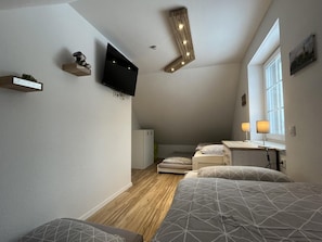 Ein gemütliches Schlafzimmer mit Bett, Nachttischlampen, Fernseher und Fenster.