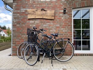 A brick building with a wooden sign reading "Alleenhaus" and two bicycles parked in front. - Alleenhuus - Hochwertiges und Luxuriöses Ferienhaus Direkt am Wariner See (Warin)