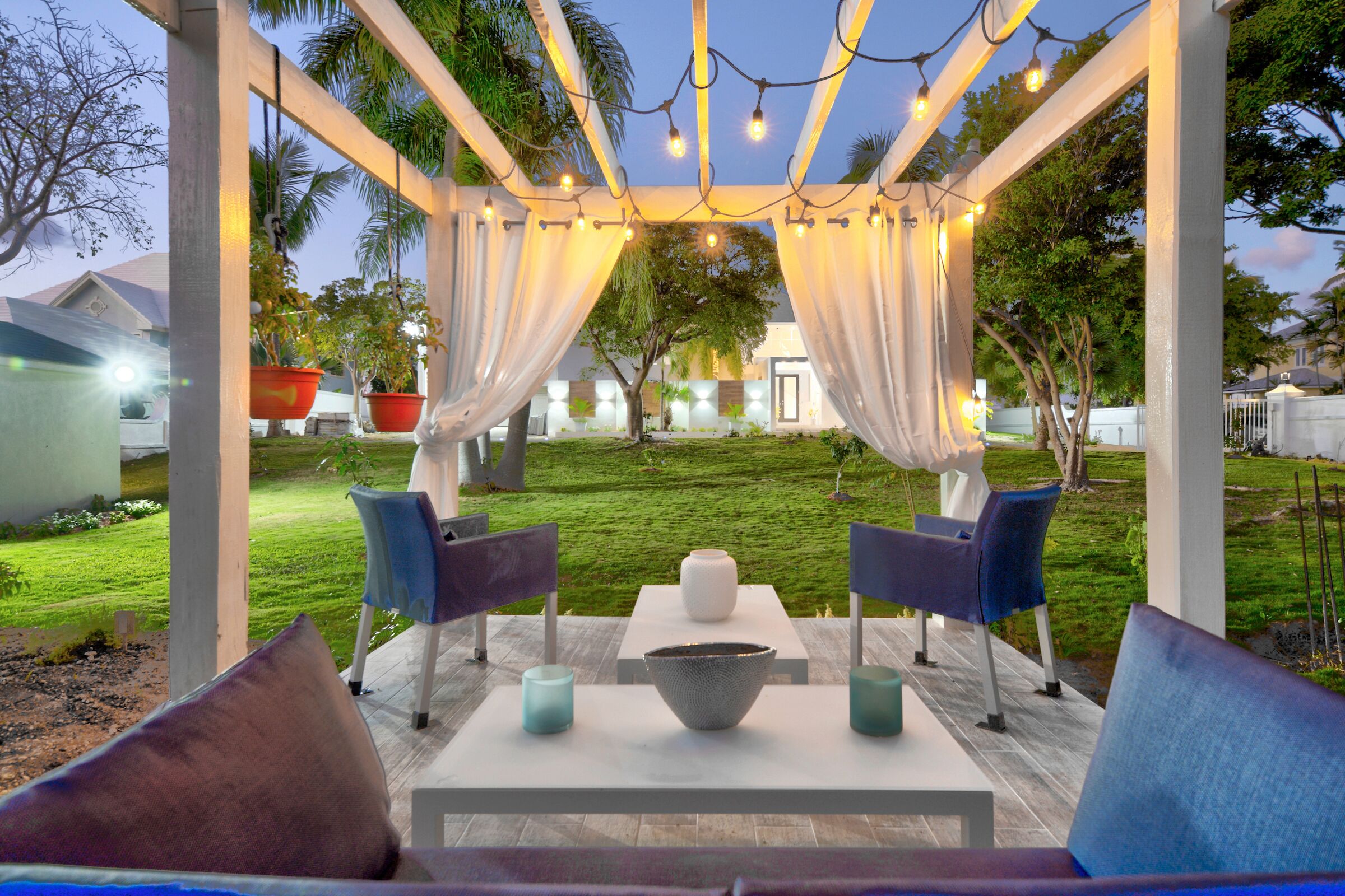 An outdoor patio area with a pergola, string lights, and seating.