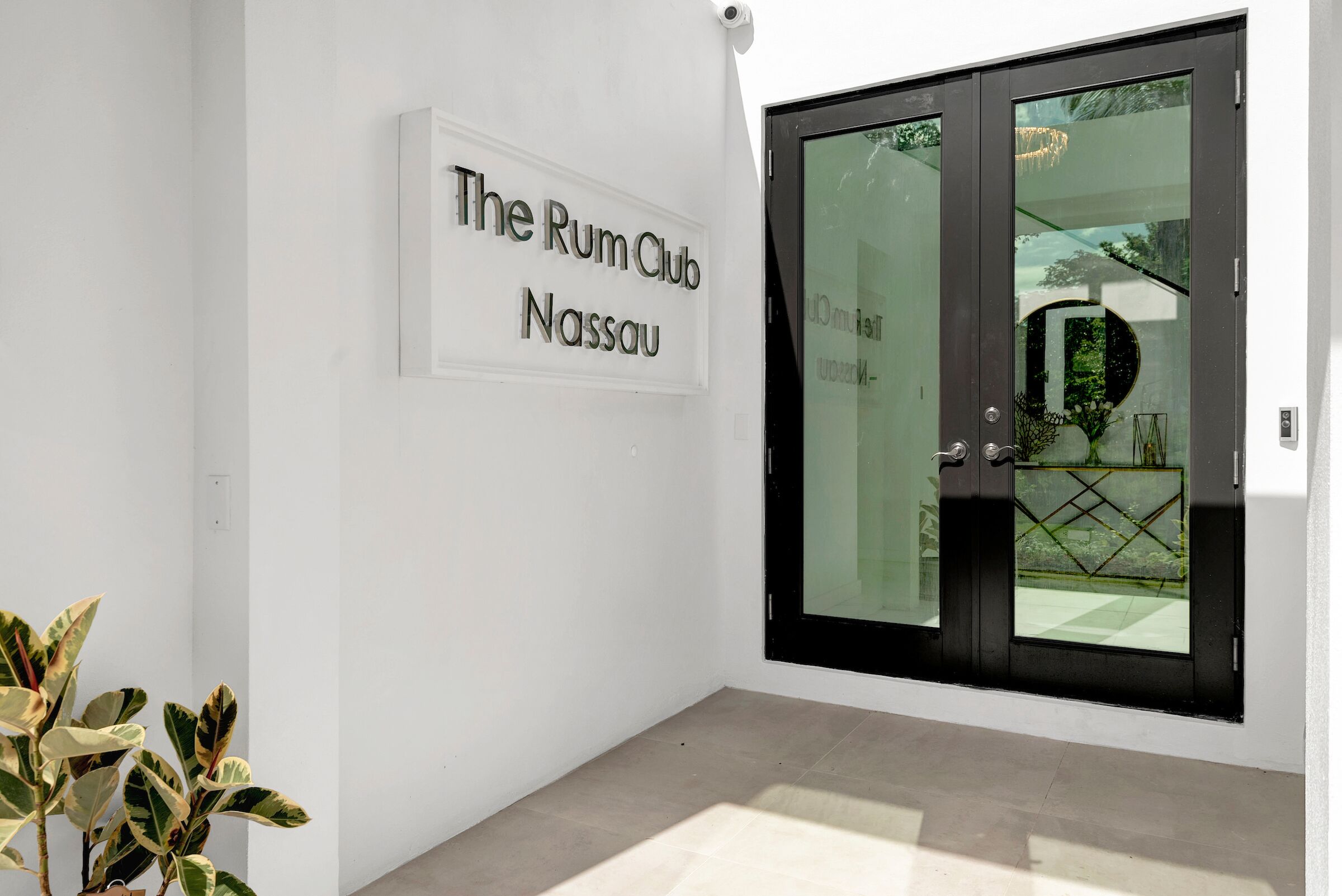 Una entrada moderna amb una porta de vidre i un rètol que diu "The Rum Club Nassau".