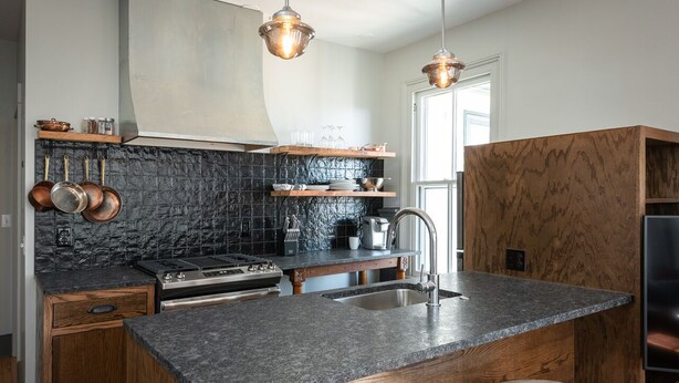 A modern kitchen with granite countertops, copper cookware, and wooden cabinetry. - Blacksmith Apartment | Lux Extended Stay in Belmont (Charlottesville)