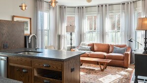 A modern kitchen with a built-in island, a brown leather sofa, and a patterned rug. - Blacksmith Apartment | Lux Extended Stay in Belmont (Charlottesville)