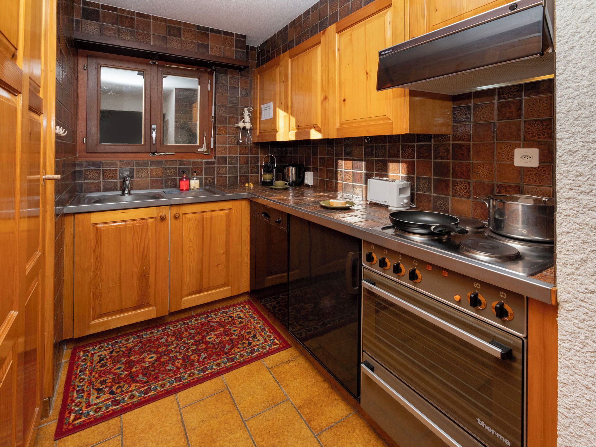 A kitchen with wooden cabinets, a stainless steel stove, and a tiled backsplash.