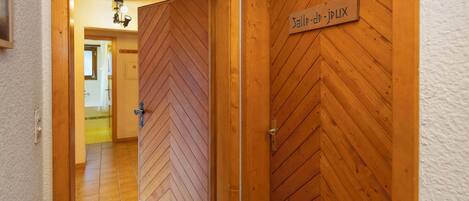 Un pasillo con puertas de madera, una de ellas con la inscripción 'Salle-de-jEUX'.