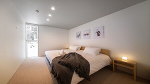 Camera da letto moderna con un grande letto, un comodino con una lampada e tre quadri appesi al muro.