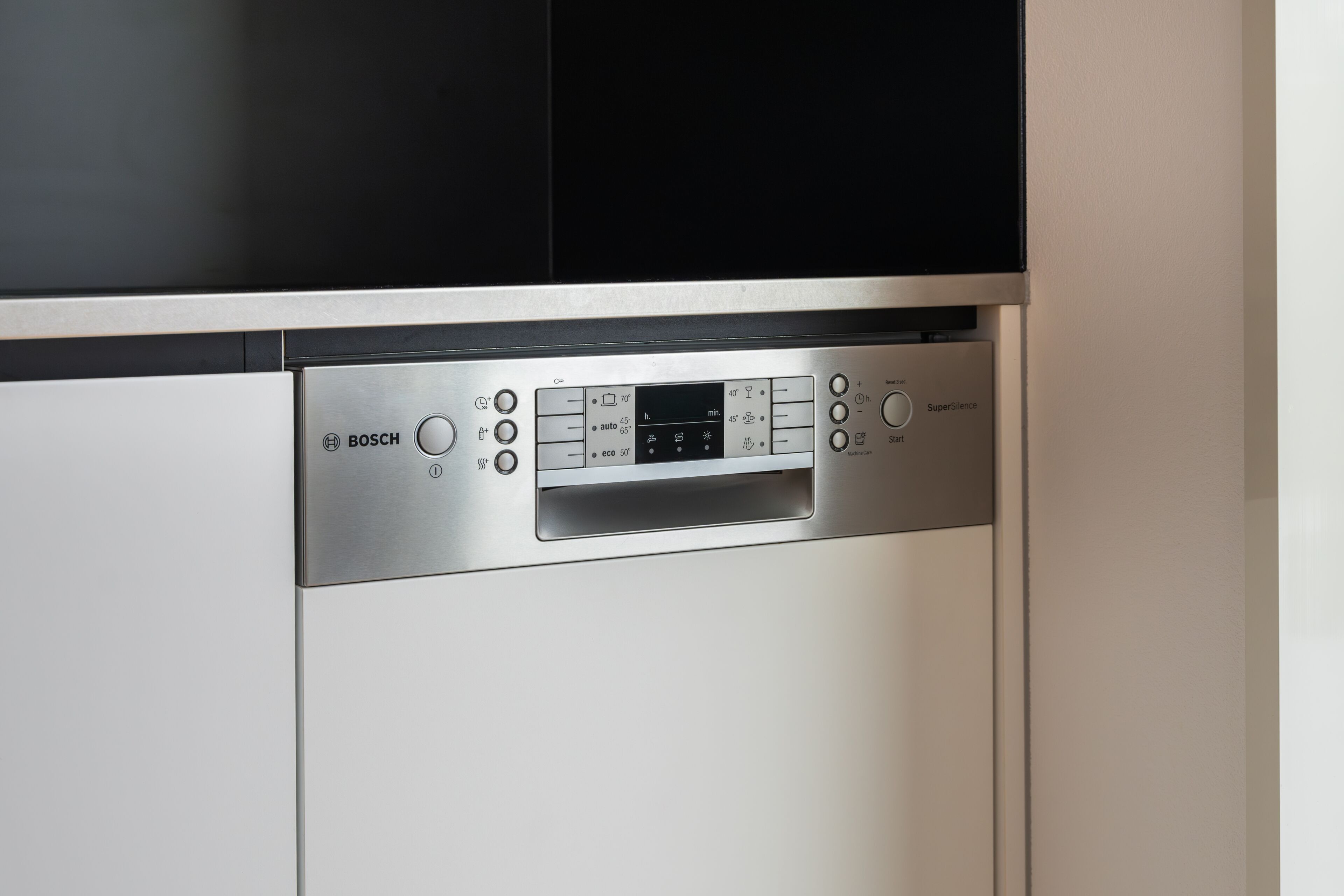 A Bosch dishwasher with a control panel, located in a kitchen with white cabinets.