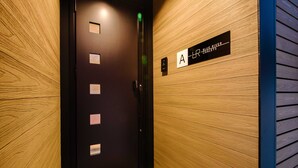 L'ingresso di un hotel con parete in legno, porta dell'ascensore nera e insegna che indica la stanza 'A' con la scritta 'Blue River Chalets'.