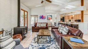 A spacious living room with a fireplace, leather sofas, a coffee table, and a large window. - Sedona Views, Casita, Trail Access (Sedona)