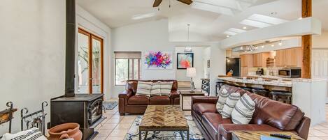 A spacious living room with a fireplace, leather sofas, a coffee table, and a large window.