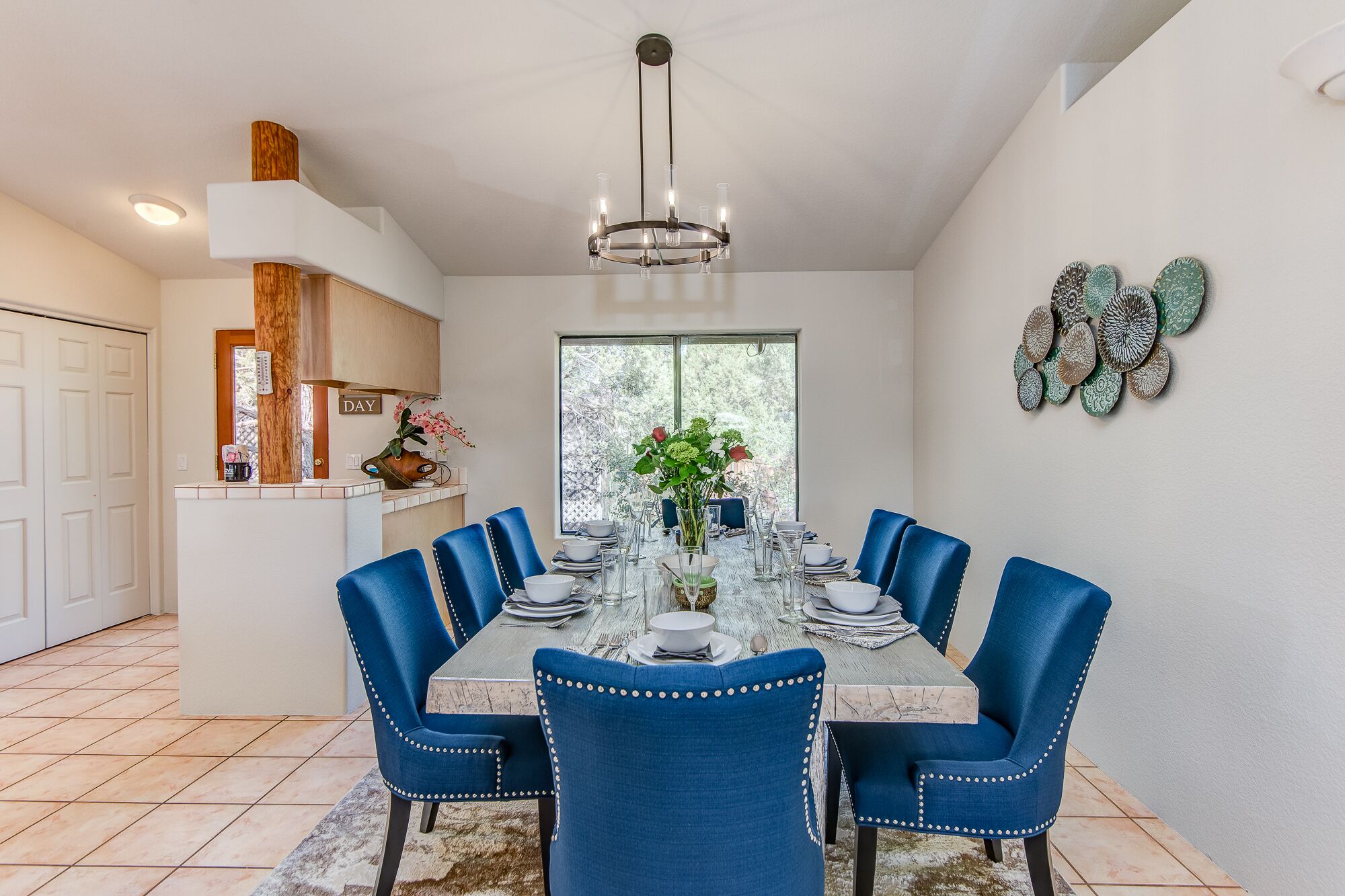 A dining room with a round table, blue upholstered chairs, and a chandelier.