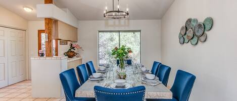 A dining room with a round table, blue upholstered chairs, and a chandelier.