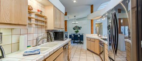 A modern kitchen with wooden cabinets, a central island, and a built-in oven.