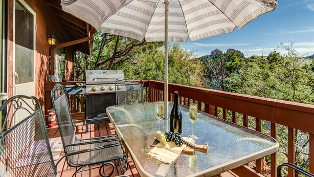 An outdoor patio with a grill, chairs, a table with a bottle and glasses, and an umbrella. - Sedona Views, Casita, Trail Access (Sedona)