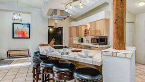 A modern kitchen with a central island, bar stools, and a dining area. - Sedona Views, Casita, Trail Access (Sedona)