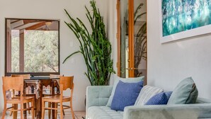 A living room with a light grey sofa, wooden dining table, chairs, and a large green plant. - Sedona Views, Casita, Trail Access (Sedona)