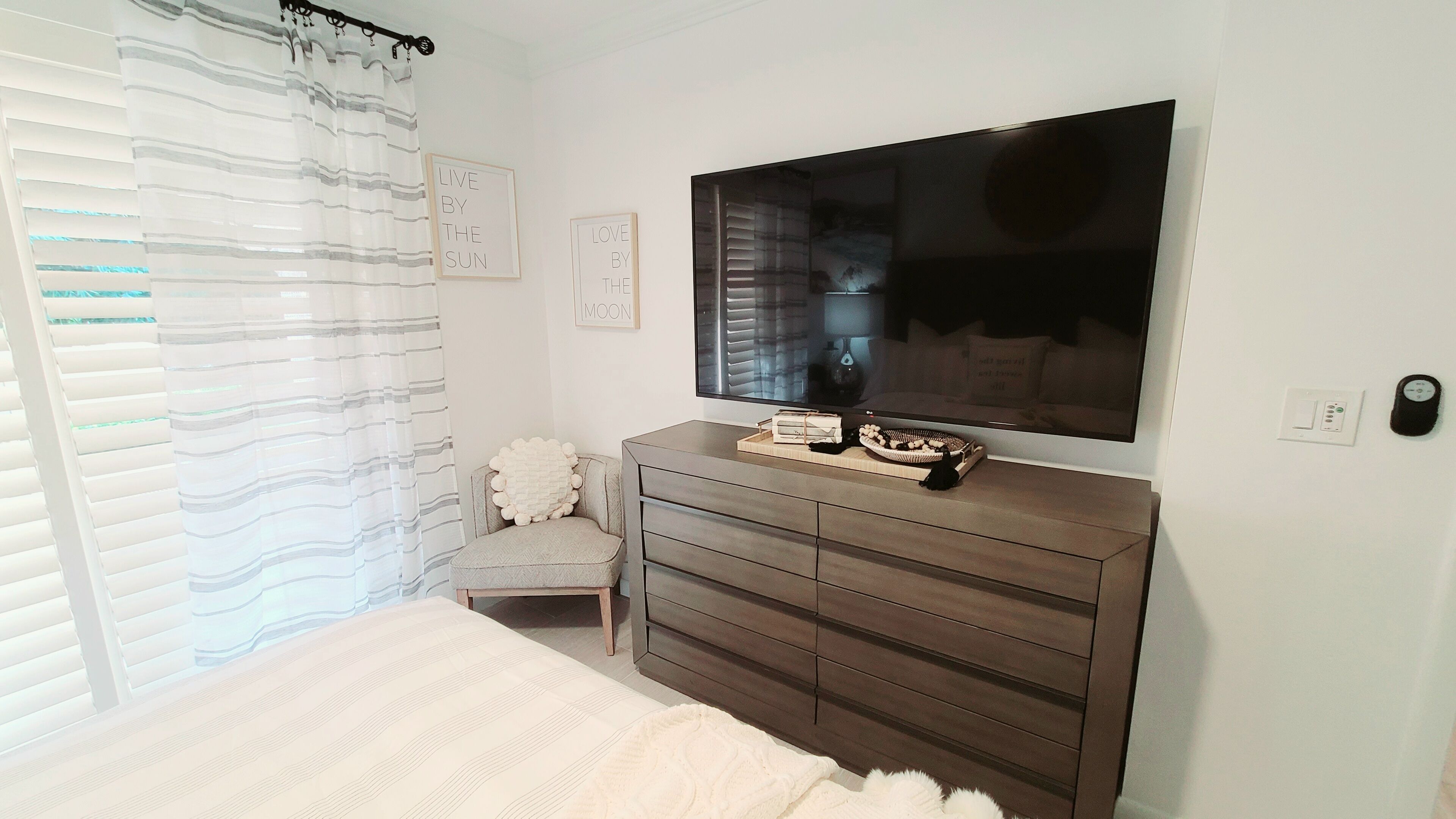 A bedroom with a bed, a dresser, a television, and a window with blinds.